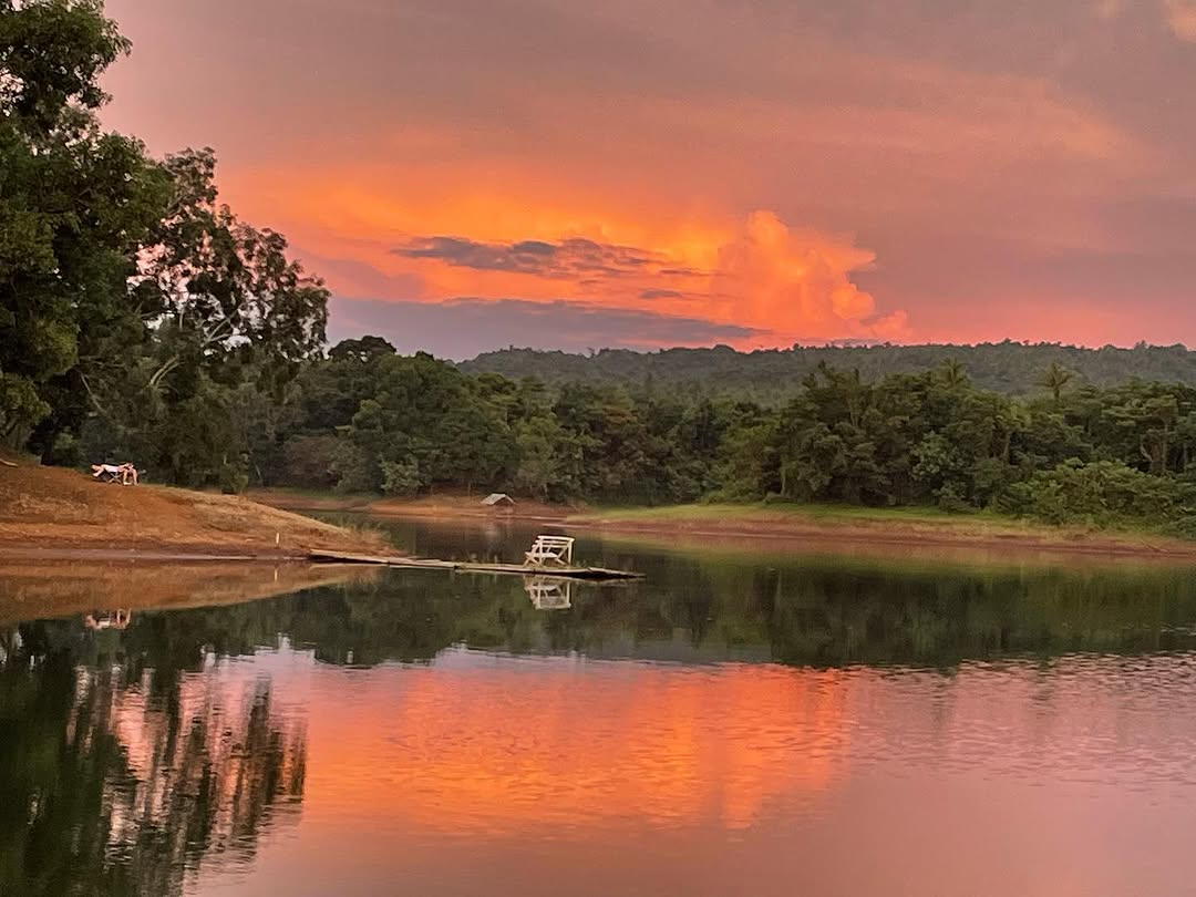 Vivid pink and orange sunset reflected in Lake Lumot, bamboo jetty in foreground