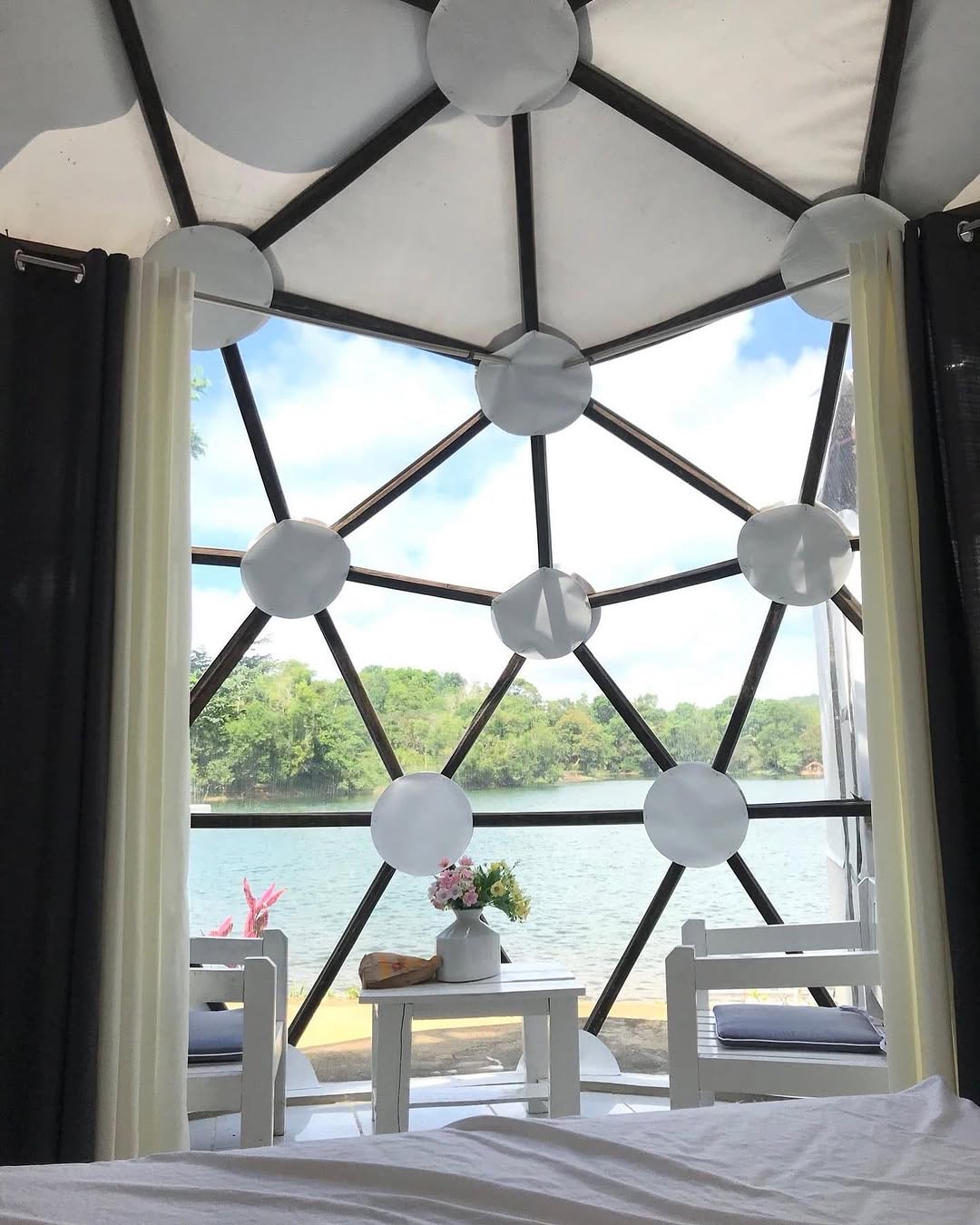 Dome Veera interior — bed with view through geodesic dome panels over the lake